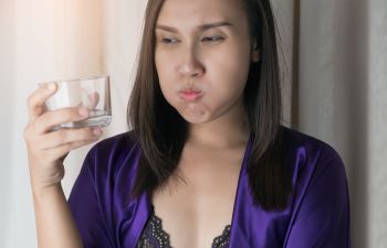 Woman suffering from acid reflux drinking water after waking up in the morning.